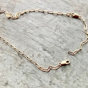 May include: A gold chain necklace with a lobster clasp closure. The chain is made of small, oval-shaped links.