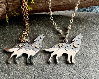 Könnte beinhalten: Zwei silberne Wolf-Anhänger-Halsketten mit goldenen und silbernen Ketten. Die Anhänger zeigen ein heulendes Wolf-Design mit Stern- und Mondakzenten. Eine Halskette hat eine goldene Kette, die andere eine silberne Kette.