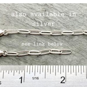 May include: Two silver chain links, each measuring approximately 1 inch in length, are laid out on a gray surface. A ruler is placed below the chains, with markings in inches. The text "also available in silver" and "see link below" are visible above the chains.
