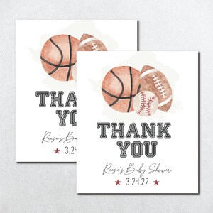 Op de afbeelding: Twee bedankkaartjes met een aquarel-illustratie van een basketbal, honkbal en voetbal. De tekst op de kaartjes luidt "Bedankt" en "Reusi's Baby Shower 3.24.22".