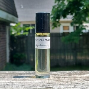 May include: A clear glass roll-on bottle with a black cap and a white label that reads "HEAVENLY MUSK" and "clayssheashop".