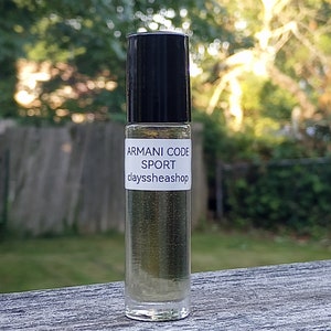 Puede incluir: Un frasco de vidrio transparente con un tapón negro y una etiqueta blanca que dice "ARMANI CODE SPORT clayssheashop".