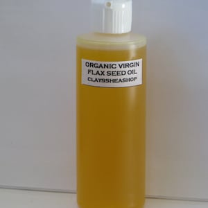 May include: A clear glass bottle with a white cap filled with a yellow liquid. The bottle has a white label that reads "ORGANIC VIRGIN FLAX SEED OIL CLAYSSHEASHOP".