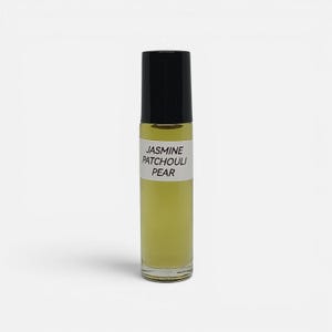 Op de afbeelding: Een doorzichtig glazen roller-parfumflesje gevuld met een lichtgele vloeistof. Het flesje heeft een zwarte cilindrische dop en een wit rechthoekig etiket met de zwarte tekst JASMINE PATCHOULI PEAR in het midden op de voorzijde.