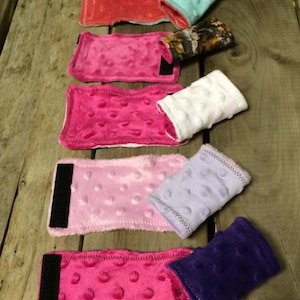 May include: A set of eight wrist cuffs in various colors, including pink, purple, white, and teal. The cuffs are made of soft, textured fabric and have a velcro closure.