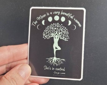 May include: A black and white sticker with a quote about the moon. The quote reads "The Moon is a very beautiful woman. She's in control -  Rumi  #moonconnection". The sticker features a tree with a woman standing on a branch, and a circle of moons around the tree.