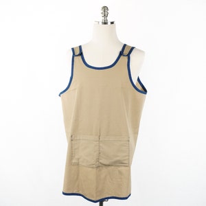 May include: A tan sleeveless apron with a blue trim and a large pocket on the front.