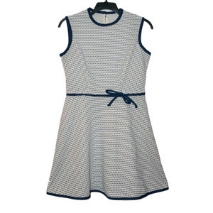 May include: A white and blue patterned sleeveless dress with a navy blue trim and a bow at the waist.
