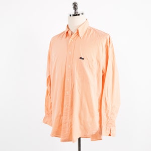 May include: A long-sleeved, orange and white checkered button-down shirt with a small logo on the left chest pocket.