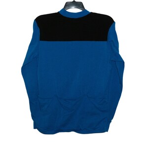 May include: A long-sleeved shirt with a black collar and a black band across the chest. The shirt is blue.