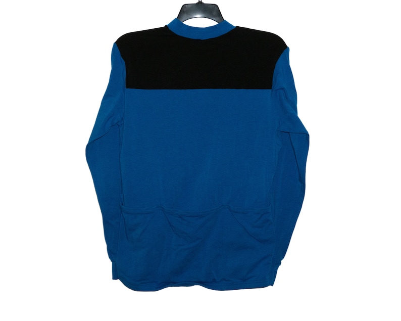 May include: A long-sleeved shirt with a black collar and a black band across the chest. The shirt is blue.