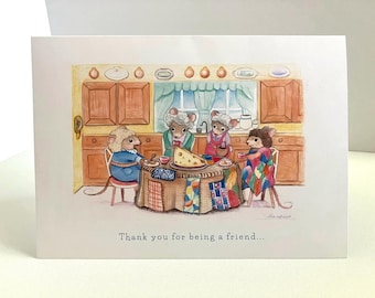 Puede incluir: Una tarjeta de felicitación con una ilustración de acuarela de cuatro ratones sentados alrededor de una mesa con un trozo de queso. Los ratones llevan ropa y están sentados en un ambiente de cocina. La tarjeta dice "Gracias por ser un amigo..."