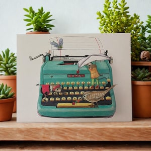 May include: A rectangular greeting card featuring a teal Royal typewriter illustration. A mouse in a red sweater, a mouse in a yellow jacket holding an umbrella, a bird, and a dragonfly are depicted. The paper reads Thank you.