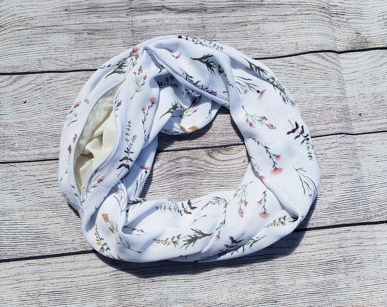 Dainty stems of wildflowers in various colors on a creamy white background with a hidden zippered pocket.