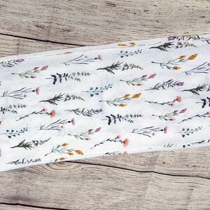 Dainty stems of wildflowers in various colors on a creamy white background with a hidden zippered pocket.