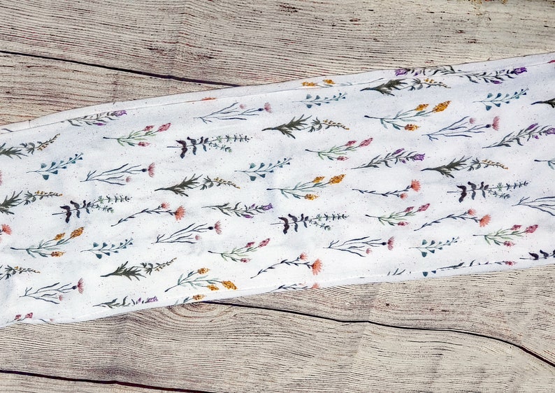 Dainty stems of wildflowers in various colors on a creamy white background with a hidden zippered pocket.