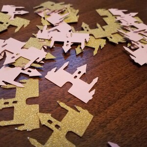 May include: Pink and gold glitter castle confetti. The confetti is shaped like a castle with a pointed roof and towers. The confetti is perfect for a princess-themed party.