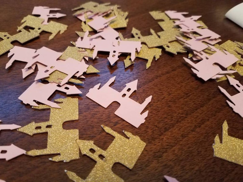 May include: Pink and gold glitter castle confetti. The confetti is shaped like a castle with a pointed roof and towers. The confetti is perfect for a princess-themed party.
