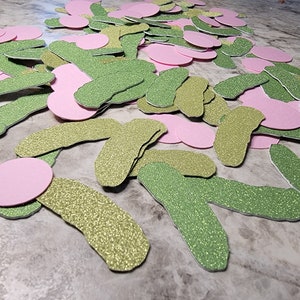 May include: A pile of green and pink glitter paper cutouts. The green cutouts are shaped like cucumbers and the pink cutouts are circles.