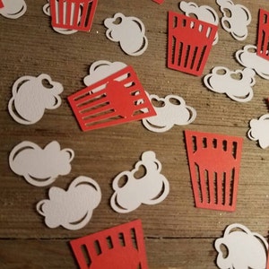 May include: Red and white paper cutouts of popcorn and popcorn boxes. The cutouts are scattered on a wooden surface.