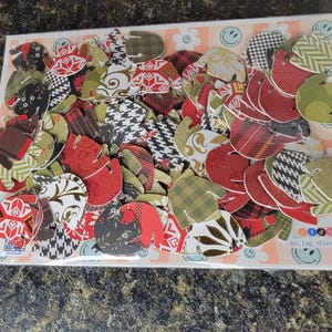 May include: A collection of colorful paper cutouts in various patterns and designs, including plaid, polka dots, and floral prints. The cutouts are in shades of red, green, brown, and white. The text "Click, tag, share" is visible in the bottom right corner of the image.