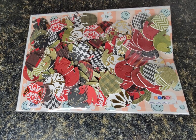 May include: A collection of colorful paper cutouts in various patterns and designs, including plaid, polka dots, and floral prints. The cutouts are in shades of red, green, brown, and white. The text "Click, tag, share" is visible in the bottom right corner of the image.