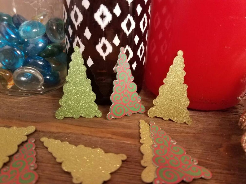 Puede incluir: Surtido de adornos de papel con forma de &aacute;rbol de Navidad con purpurina. Algunos son verdes y otros son rojos y verdes con un patr&oacute;n de espiral.