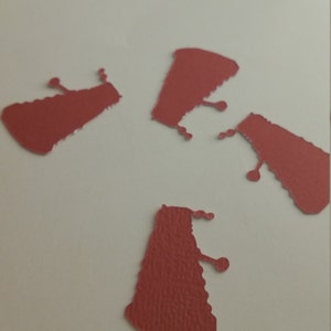 May include: Four red paper cutouts of the iconic Dalek from the Doctor Who television series. The Daleks are a fictional alien race known for their distinctive design and catchphrase, "Exterminate!"