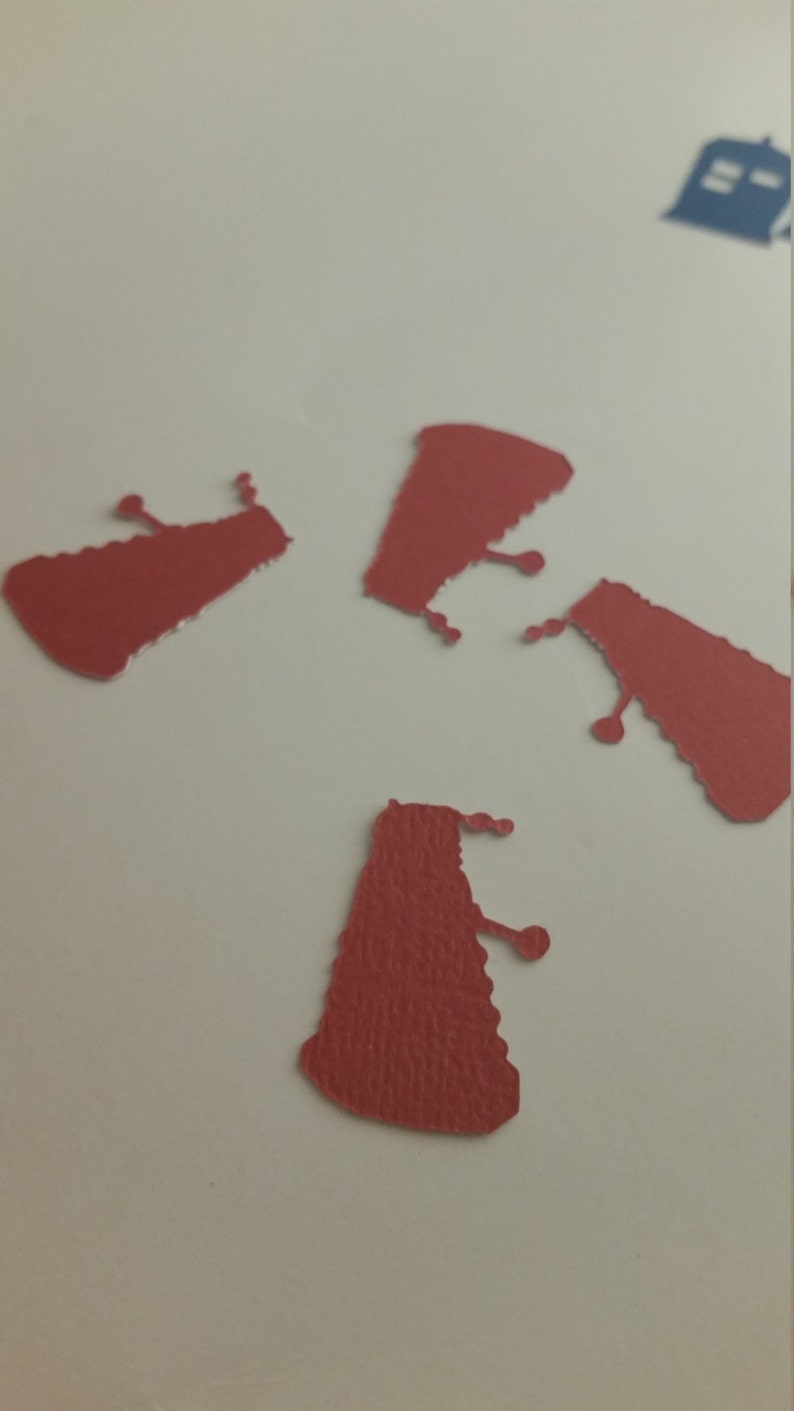May include: Four red paper cutouts of the iconic Dalek from the Doctor Who television series. The Daleks are a fictional alien race known for their distinctive design and catchphrase, "Exterminate!"