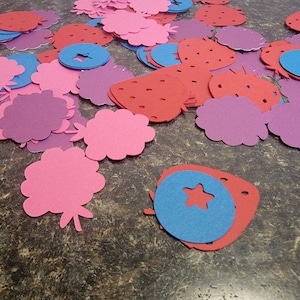 May include: Assortment of felt cutouts in pink, red, purple, and blue. The shapes include strawberries, flowers, and circles with stars.