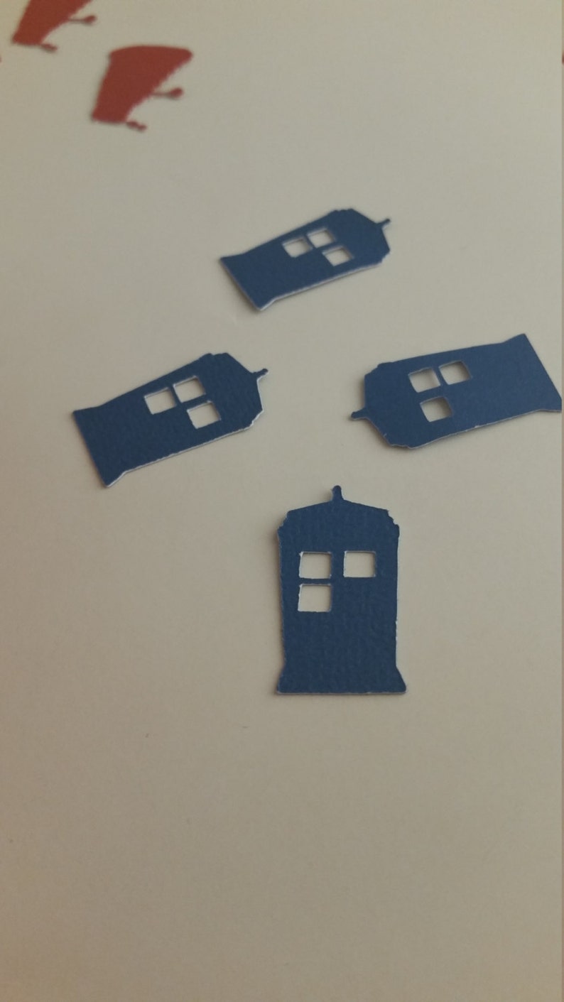 May include: Four blue paper cutouts of the TARDIS, the time machine from the Doctor Who television series. The cutouts are on a white background.