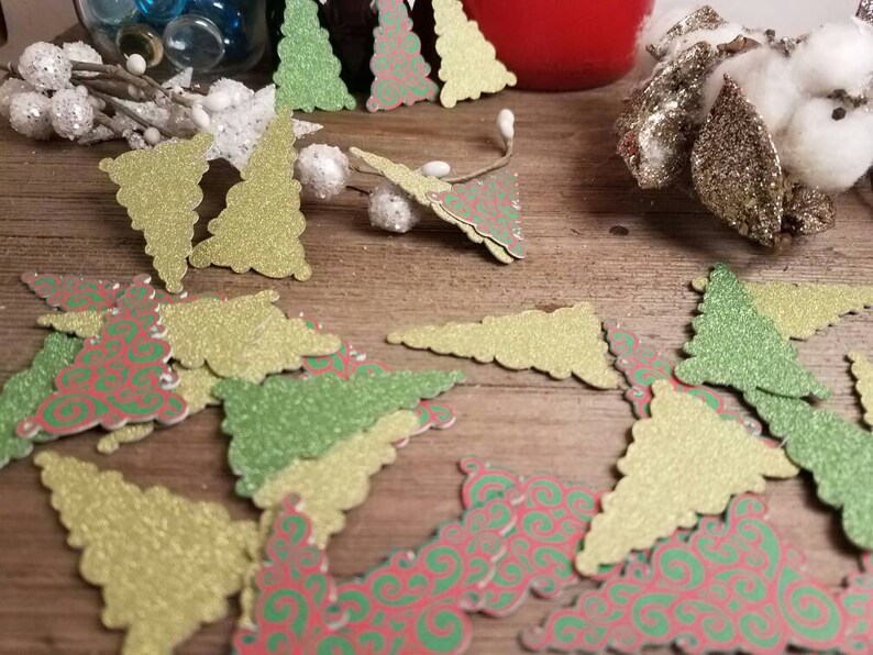 Puede incluir: Surtido de recortes de &aacute;rboles de Navidad con purpurina en verde, dorado y rojo con un patr&oacute;n de espiral.