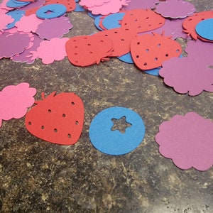 May include: Assortment of felt cutouts in the shapes of strawberries, blueberries, and raspberries. The cutouts are in shades of red, pink, blue, and purple.