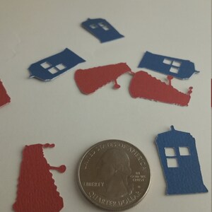 May include: Blue and red paper cutouts of the TARDIS and Daleks from the Doctor Who television series. The cutouts are scattered on a white surface next to a US quarter.