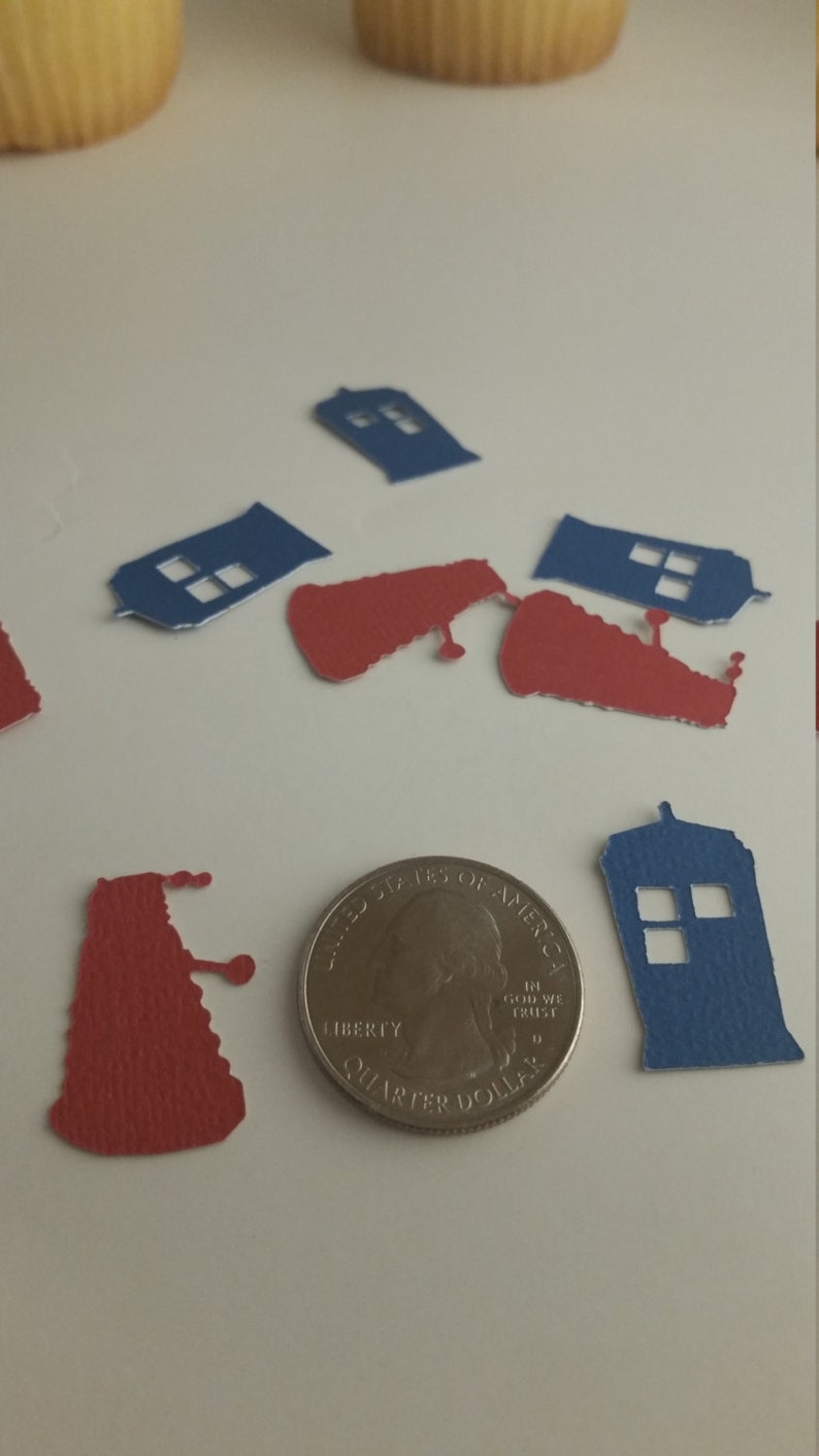 May include: Blue and red paper cutouts of the TARDIS and Daleks from the Doctor Who television series. The cutouts are scattered on a white surface next to a US quarter.