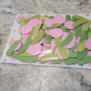 May include: A bag of pink and green glitter confetti. The confetti is in the shape of circles and long, thin rectangles.
