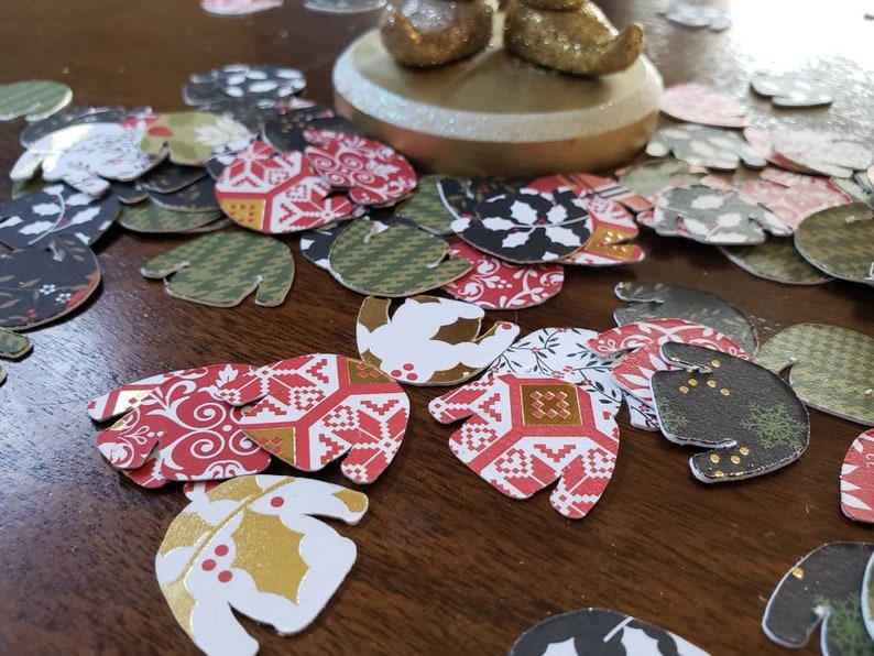 May include: Assortment of colorful paper cutouts in the shape of mittens. The cutouts feature various patterns including red and white, black and white, and green and gold.