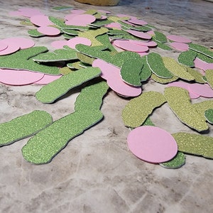 May include: A pile of green and pink glitter paper cutouts in the shape of a worm and circles.