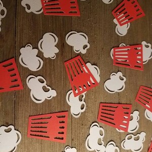 May include: Red and white paper cutouts of popcorn and popcorn boxes. The popcorn cutouts are white and the popcorn boxes are red with white stripes.