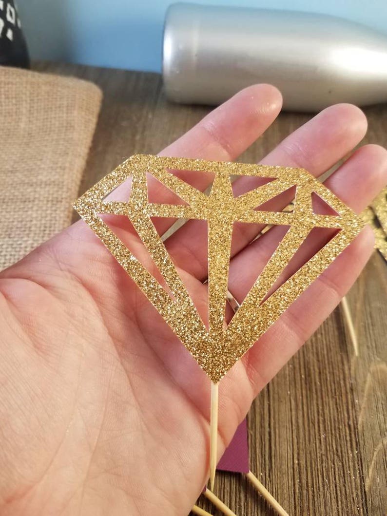 Pu&ograve; includere: Topper per cupcake a forma di diamante dorato con glitter e un bastoncino di legno.