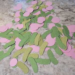 May include: A pile of green and pink glitter paper cutouts. The cutouts are shaped like pickles and circles.