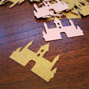 May include: A pile of pink and gold glitter castle confetti. The castles are cut out of paper and have a sparkly finish.
