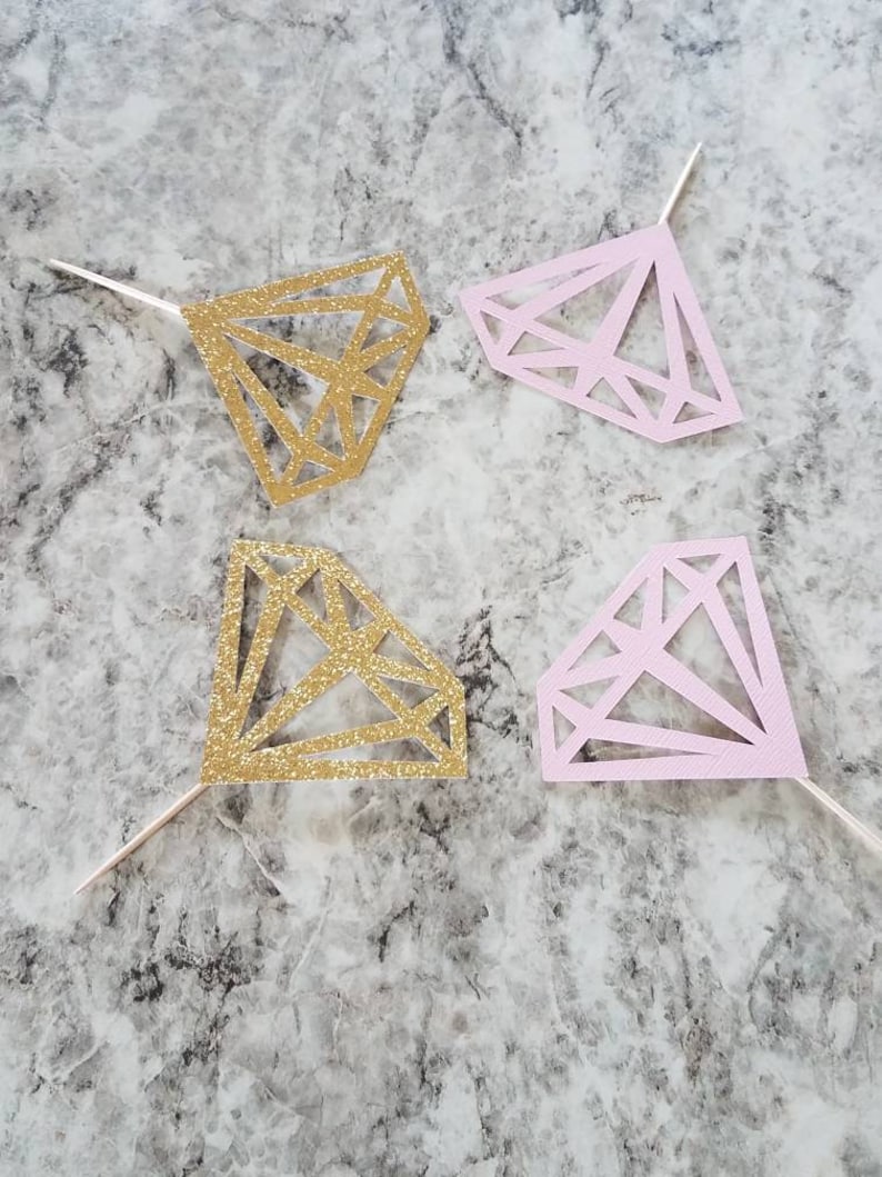 Pu&ograve; includere: Quattro topper per torta a forma di diamante, due con glitter dorati e due rosa. I topper sono fatti di carta e hanno un bastoncino sul retro per inserirli in una torta.