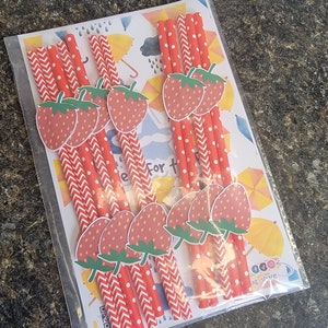 May include: A package of red and white striped paper straws with strawberry designs. The straws are packaged with a colorful card that says "Celebrate For The Little Ones".