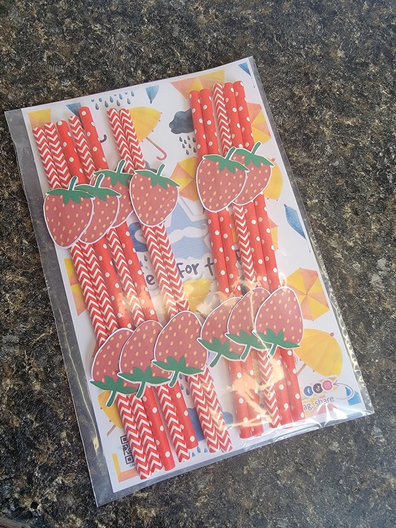 May include: A package of red and white striped paper straws with strawberry designs. The straws are packaged with a colorful card that says "Celebrate For The Little Ones".