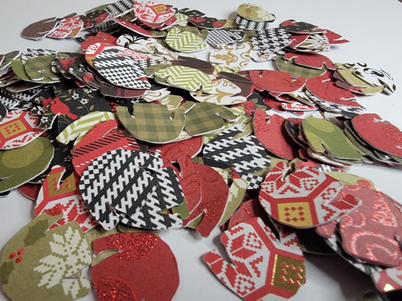 May include: A pile of red, green, and white paper mitten shapes with various patterns. The mittens are made of paper and have a festive holiday theme.