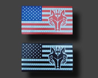 May include: Two rectangular patches with an American flag design and a wolf head emblem. One is red, white, and blue, the other black, white, and grey. The patches have a reflective surface, suitable for visibility.