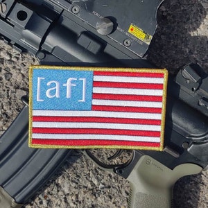 May include: A gold-trimmed patch with a blue and red American flag design. The patch has the letters "[af]" in white on the blue portion of the flag.