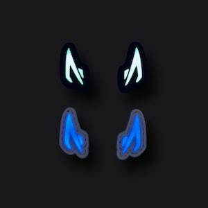 May include: Four glow-in-the-dark stickers shaped like horns. Two are green and two are blue.