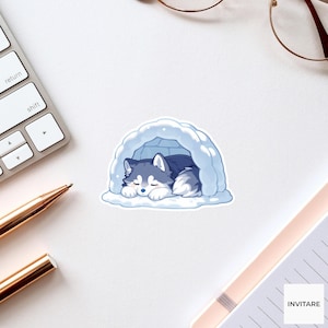 May include: A die-cut sticker featuring a cartoon illustration of a grey and white husky puppy sleeping inside a light blue igloo. The puppy has closed eyes and is curled up in a resting position within the rounded structure of the ice shelter.